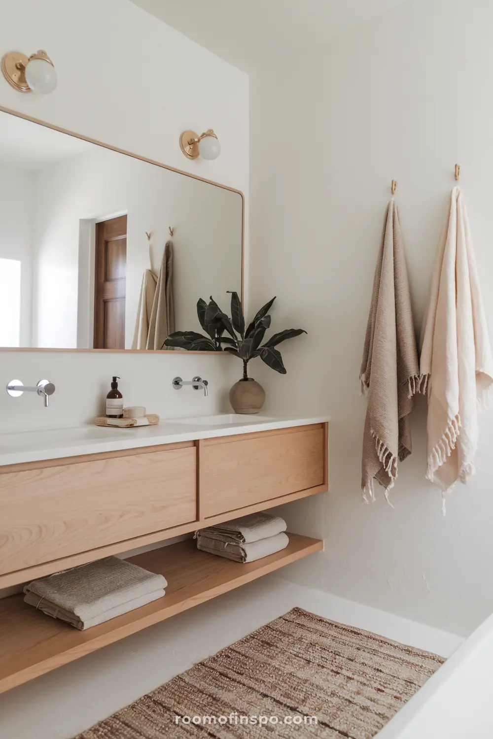 A Scandinavian-bohemian bathroom with a light wood floating vanity, white walls, and simple, airy decor for a calm and minimalist atmosphere.