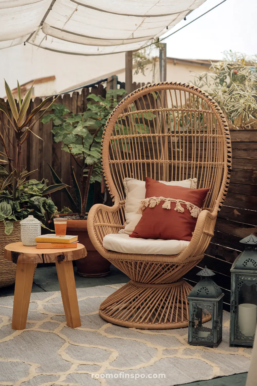A comfortable reading nook on a patio with a rattan chair, canopy, and side table in boho style.