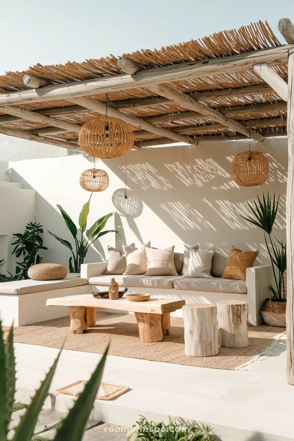 A cozy outdoor seating area with a thatched roof, wicker lanterns, and a natural wood coffee table.