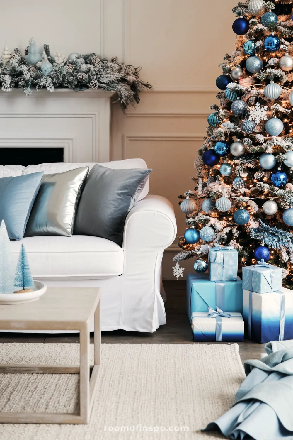 A stunning Christmas tree with blue and silver ornaments stands next to a white sofa in a festive living room.