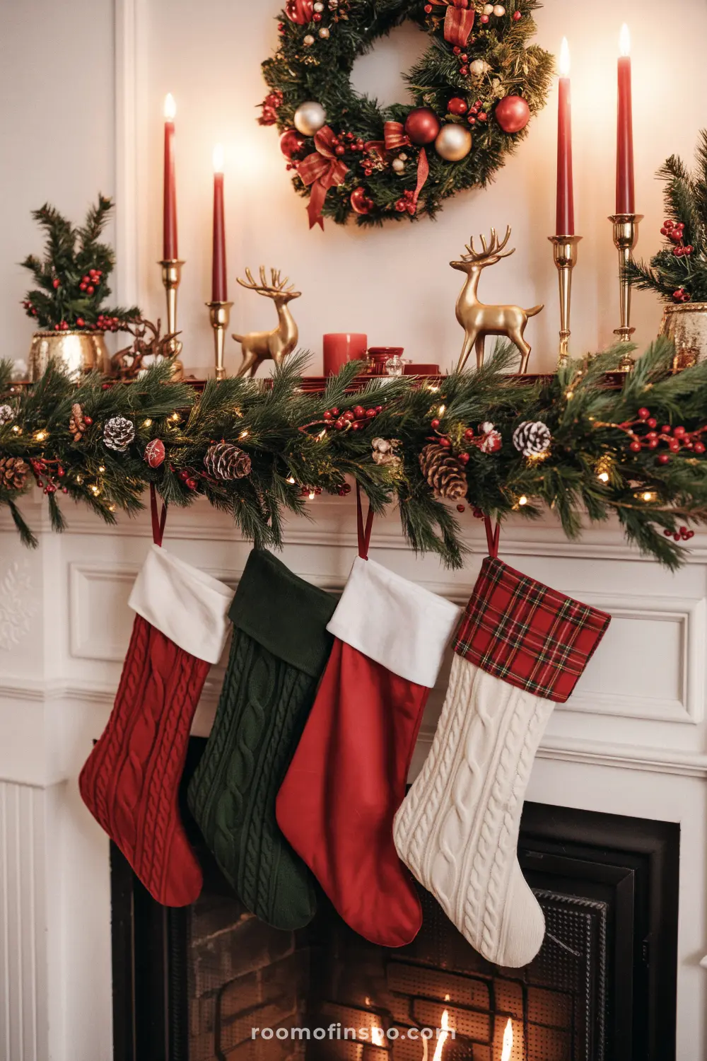 A cozy, classic Christmas mantel featuring a lush garland, red candles, golden reindeer, and four colorful hanging stockings.