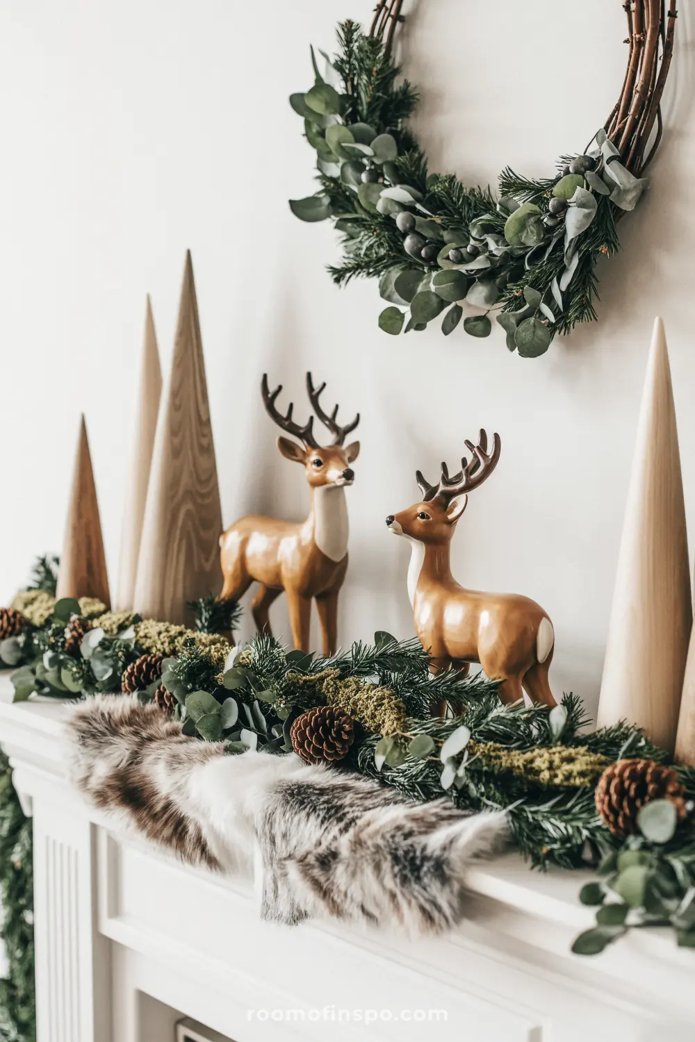 A charming woodland Christmas mantel with ceramic deer, wooden trees, a fur runner, and a eucalyptus and pine garland.