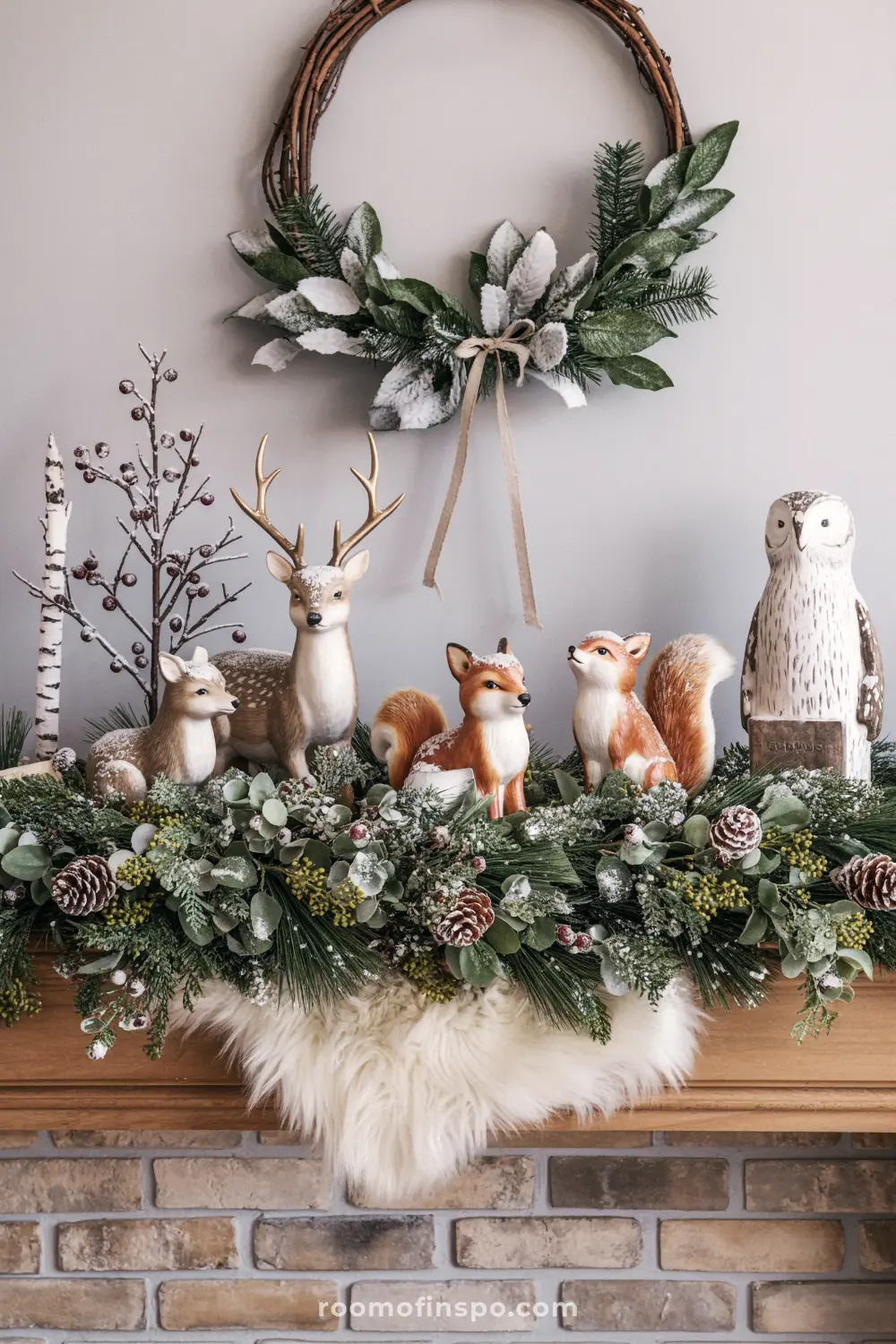 A rustic woodland Christmas mantel featuring a lush frosted garland, a fur throw, and ceramic figurines of deer, foxes, and an owl.