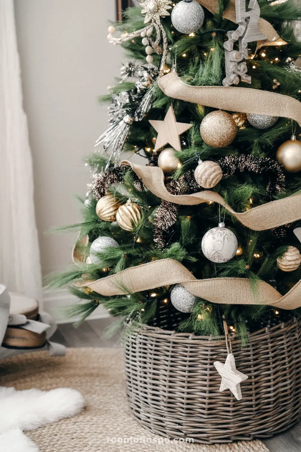 A cozy and classy Christmas tree with gold and silver ornaments, burlap ribbon, and a woven basket tree collar.