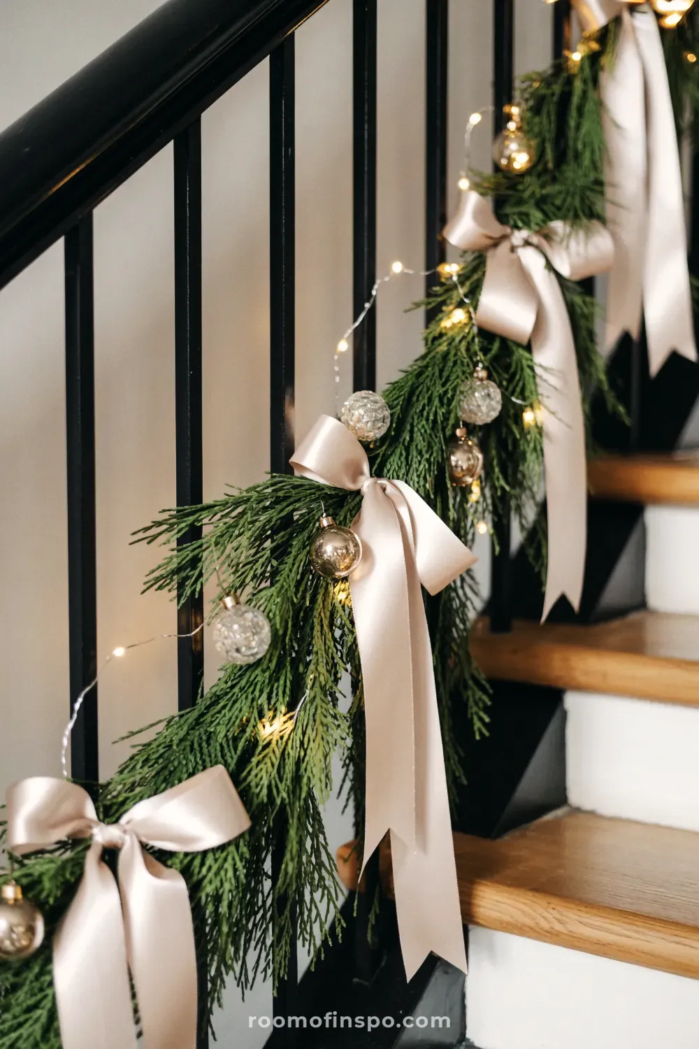 An elegant and classy Christmas staircase with lush greenery garland, champagne satin bows, and sparkling gold and clear baubles.