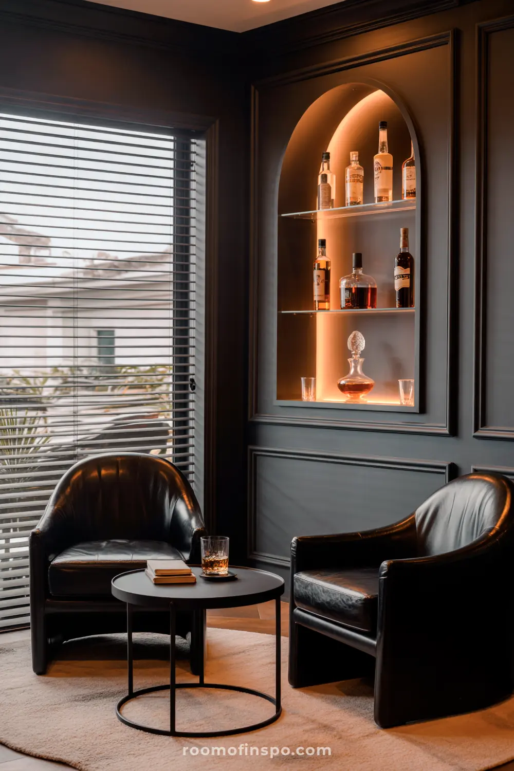 A Classy Man Cave with two black leather armchairs, a round table with a drink, and an illuminated arched display shelf showcasing various liquor bottles.