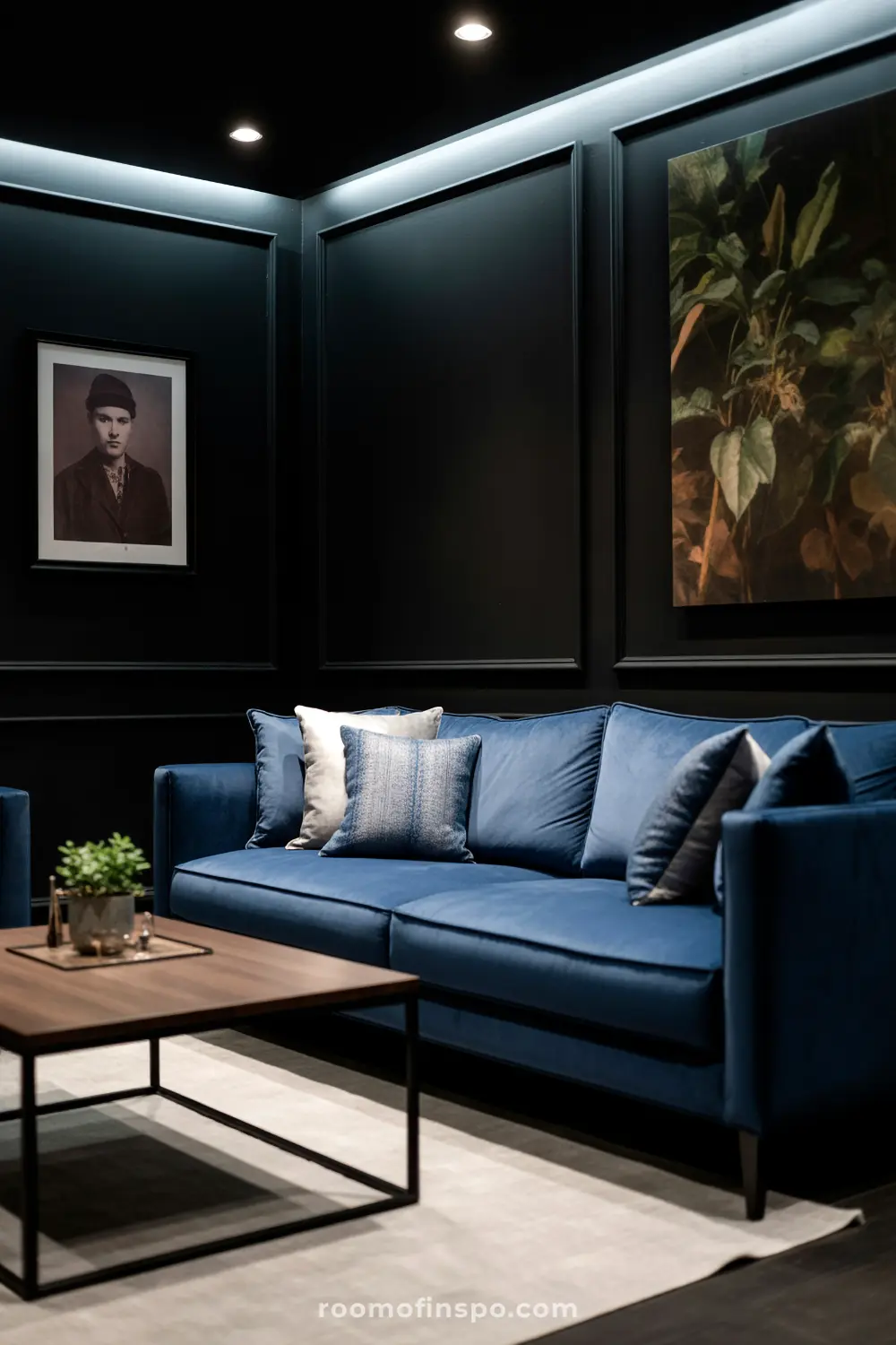 A Classy Man Cave with a deep blue sofa adorned with pillows, a modern coffee table, and dark paneled walls featuring framed artwork.