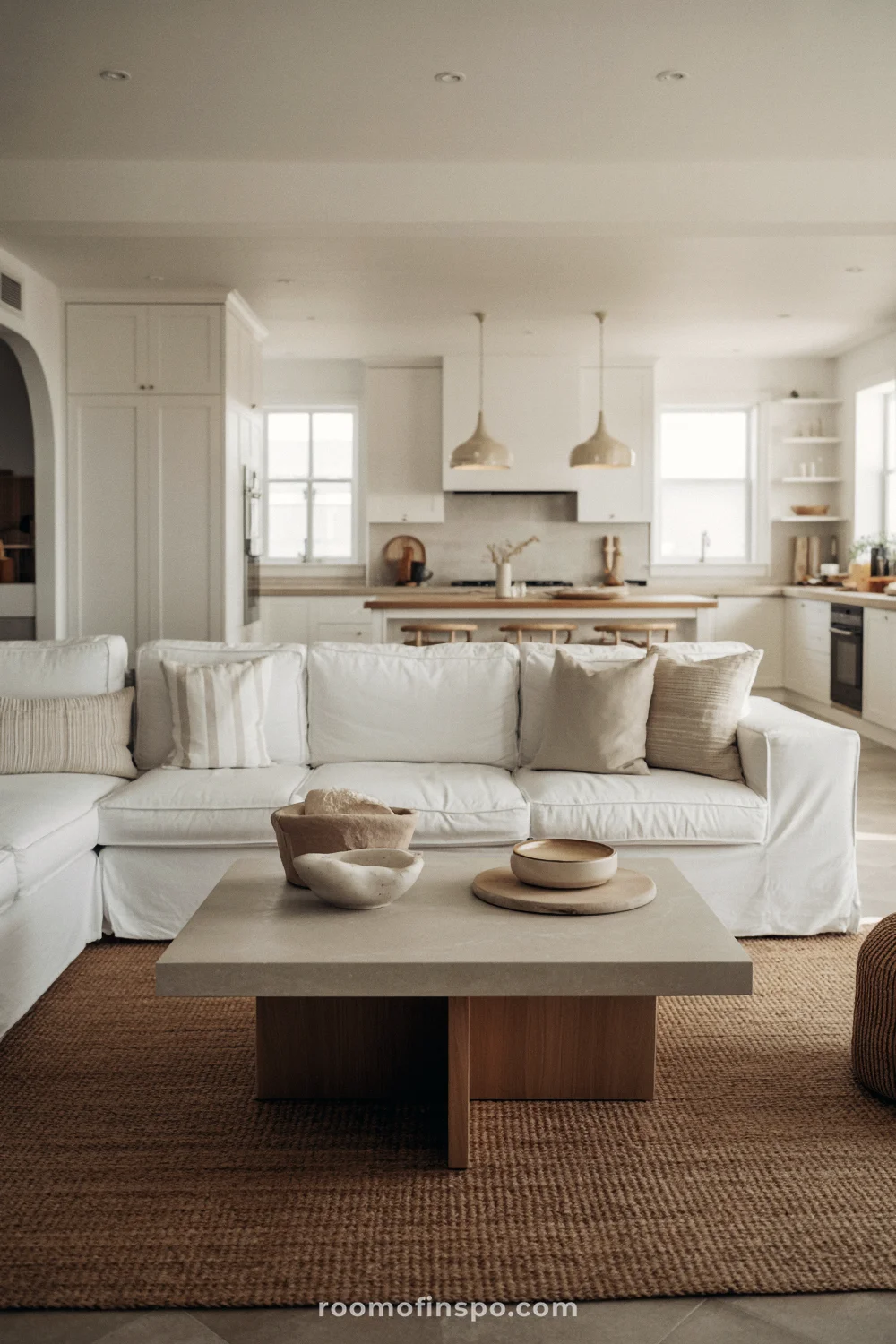 Modern coastal open-plan living room and kitchen with white, beige, and soft wood tones.