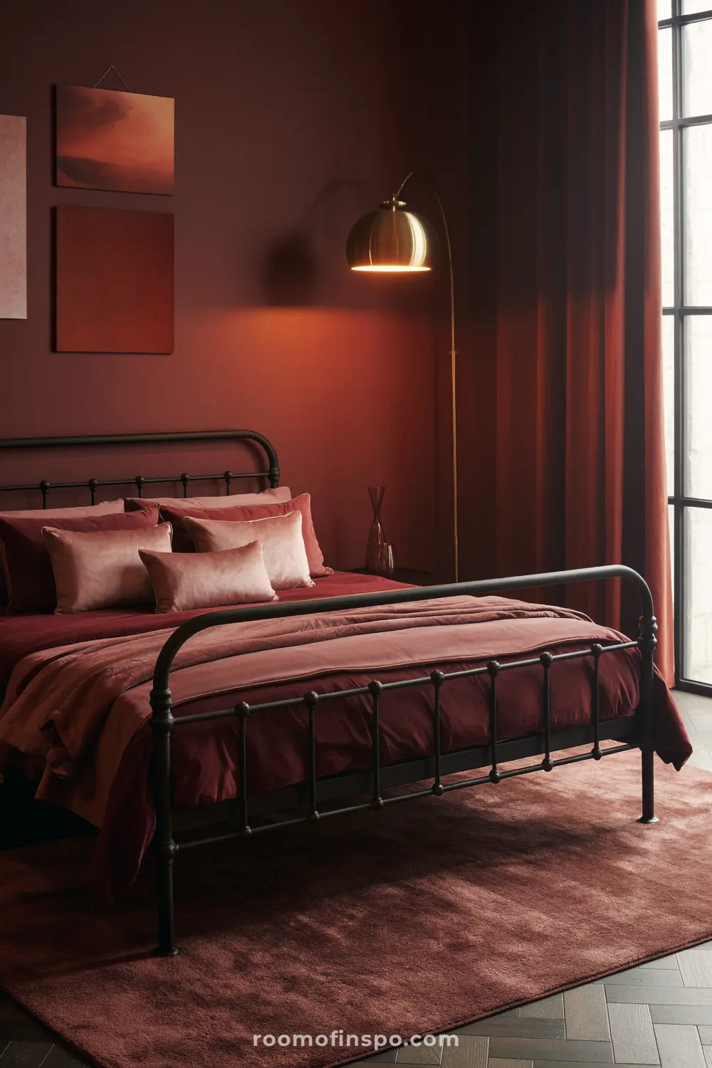 A dark and moody feminine bedroom with deep red walls, bedding, and curtains, and a black wrought iron bed.