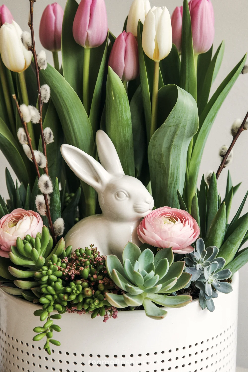 White ceramic planter with tall tulips, pink blooms, bunny, and pussy willow branches.