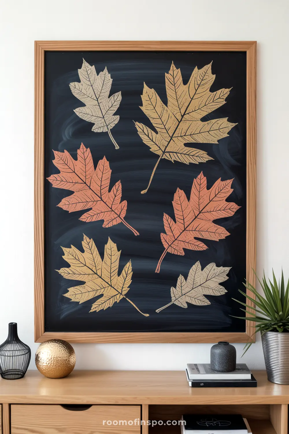 A framed chalkboard displays a beautiful array of outlined fall leaves in various autumn hues.