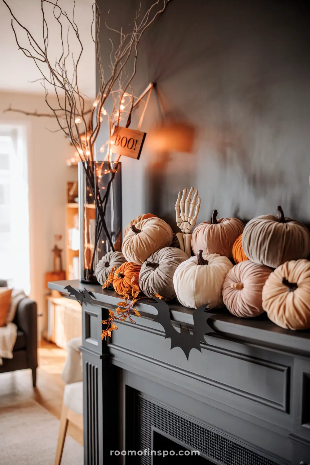 A mantel is decorated with an array of velvet pumpkins, spooky bats, and illuminated branches, creating festive fall home decor for autumn Halloween.
