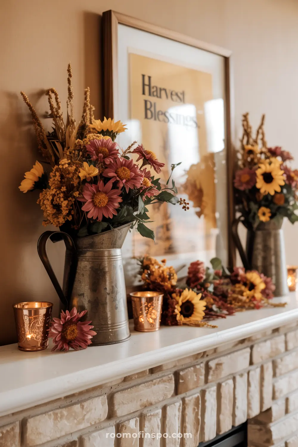 A charming fall mantel adorned with vibrant autumn flower arrangements in rustic pitchers, glowing votives, and a "Harvest Blessings" sign.