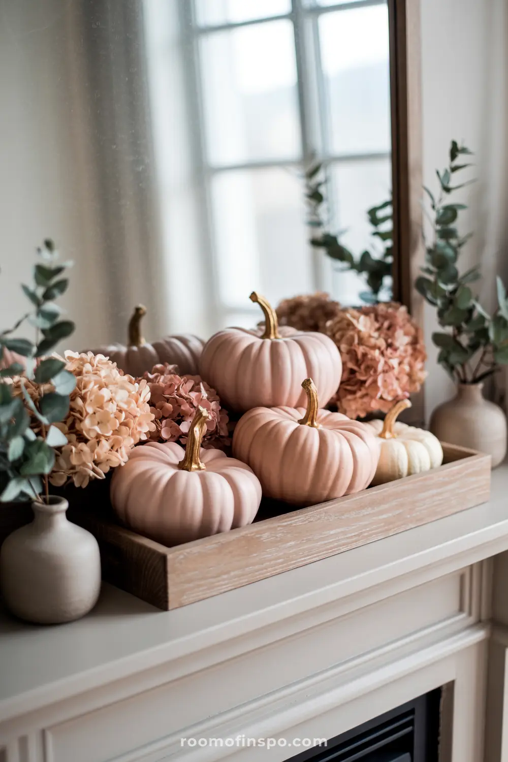 A lovely fall mantel showcases a wooden tray filled with soft pink pumpkins and dried hydrangeas, creating a beautiful autumn vignette.