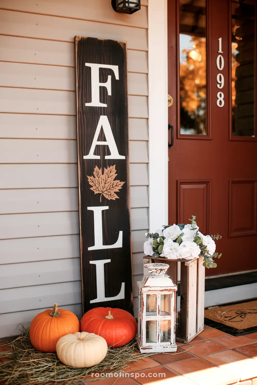 A "FALL" sign with a maple leaf decorates a front porch, featuring pumpkins and a lantern for autumn ambiance.