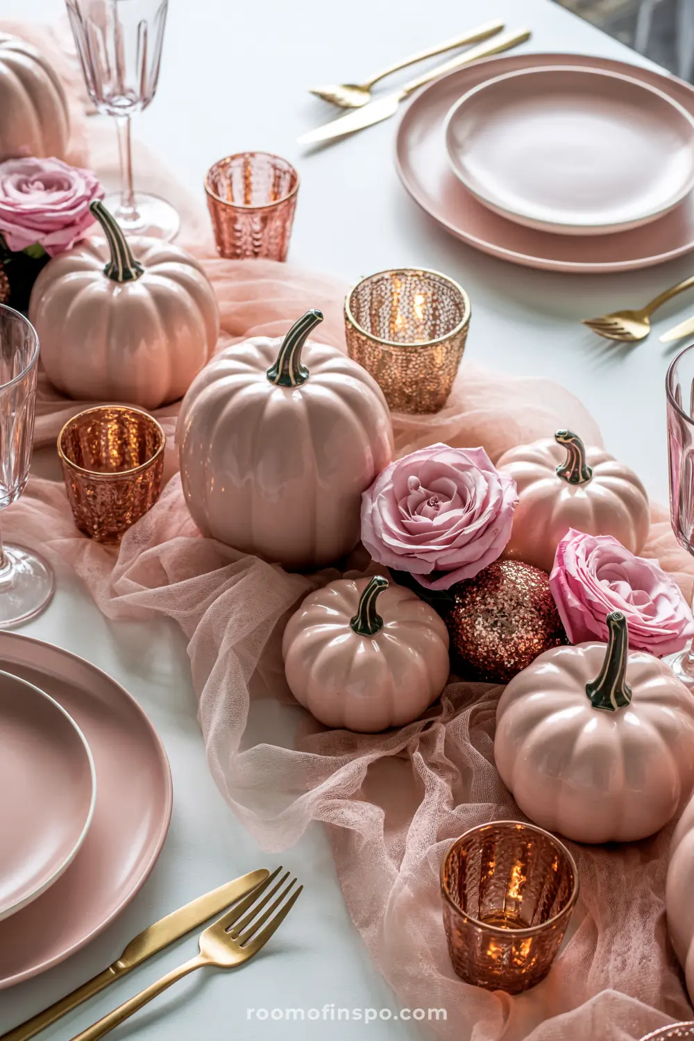A delicate Halloween centerpiece with an unexpected pink twist, featuring pink pumpkins, roses, and glittering orbs on a sheer pink runner.