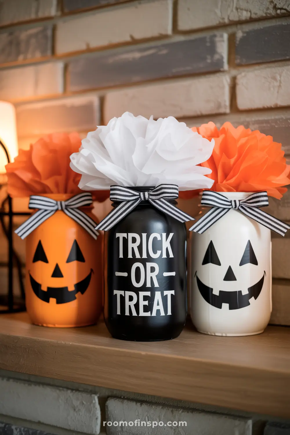 A cute Halloween centerpiece displaying painted mason jars designed as jack-o'-lanterns and "Trick-or-Treat" with tissue paper flowers.