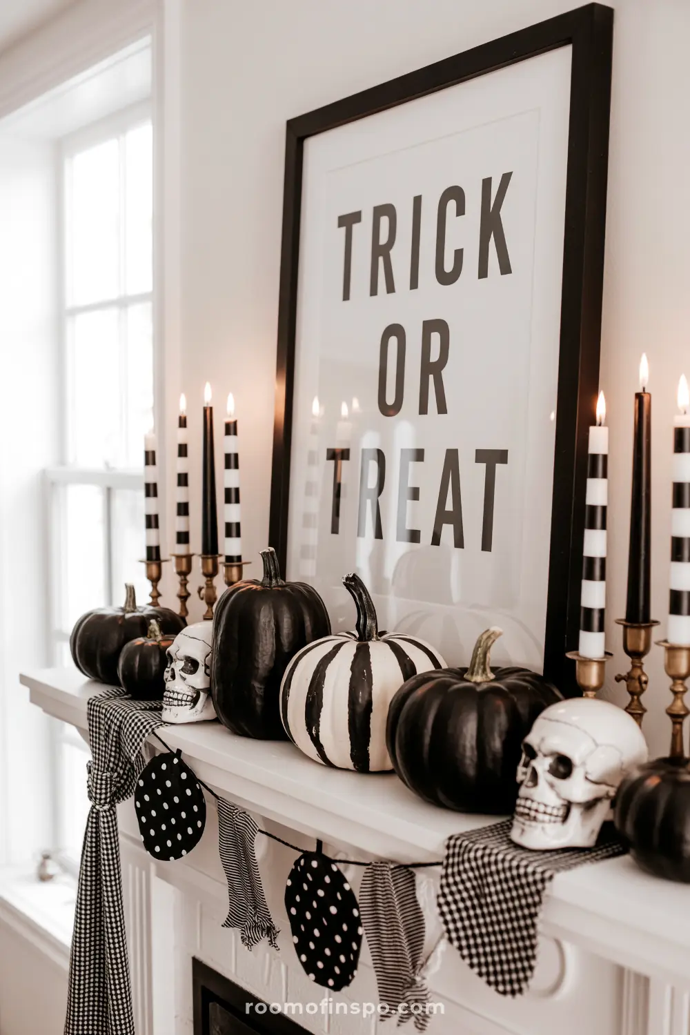 A black and white themed Halloween mantel displays "Trick or Treat" art, black and striped pumpkins, skulls, and elegant candlesticks with checkered garland.