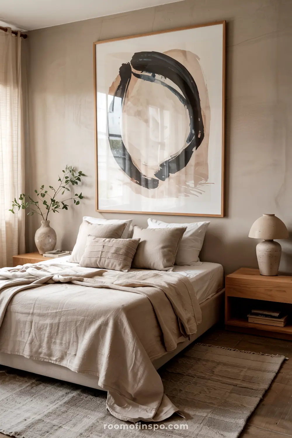 A modern bedroom with a headboard-free bed, neatly dressed in beige and white linens, accompanied by wooden nightstands, a ceramic lamp, and a large abstract painting above the bed.