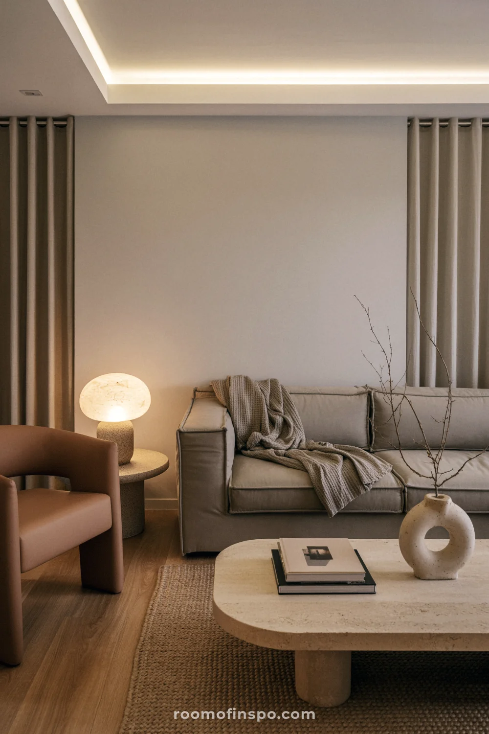 Warm neutral living room with oak floors, travertine coffee table, and soft lamp lighting.