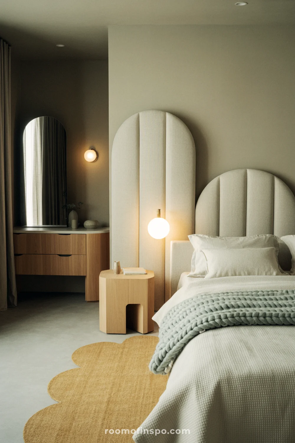 Bedroom with arched headboard, rounded nightstands, half-moon mirror, and globe wall sconces.