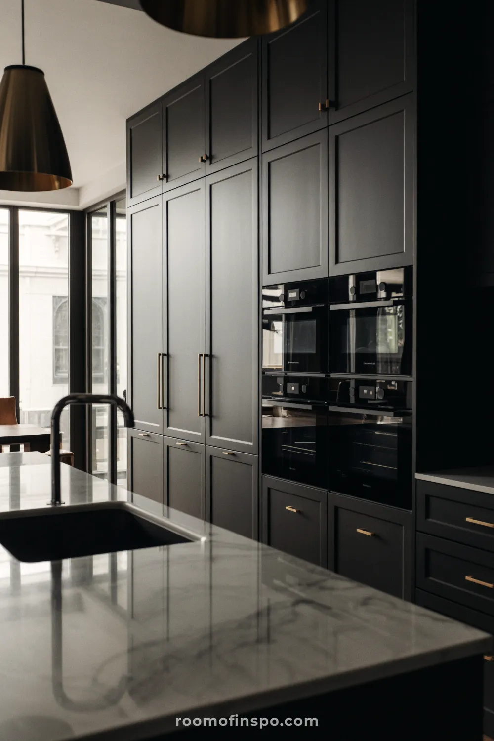 This luxurious kitchen features a mix of dark and light matte textures, showcasing a large island and high-end built-in oven.