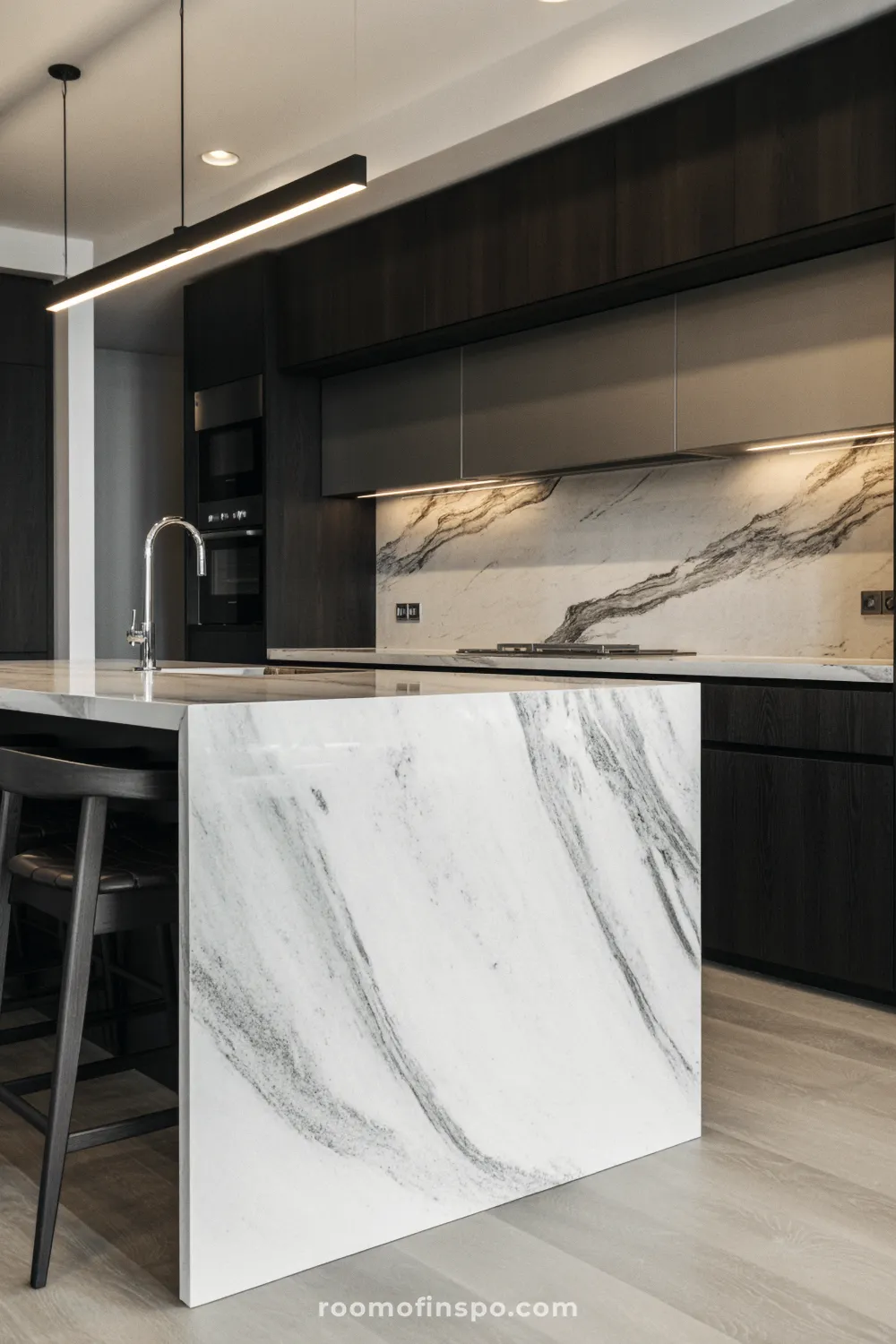 A pristine, minimalist kitchen featuring a large island with white quartz countertops and a modern, high-contrast black faucet.