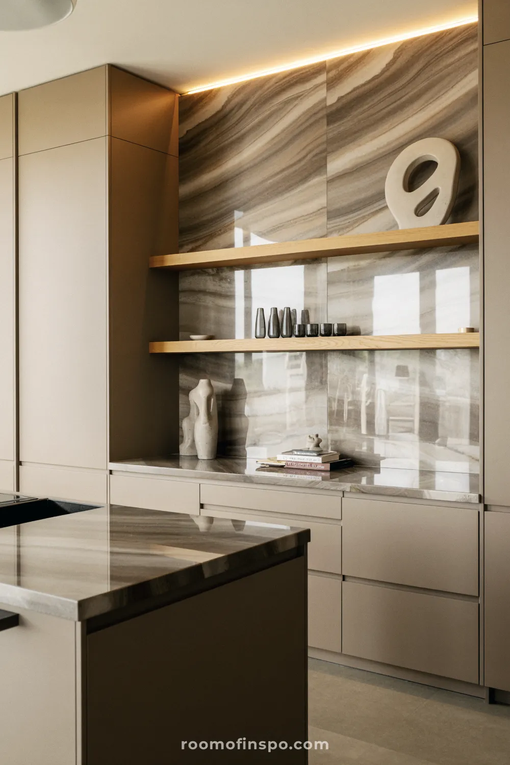 A minimalist kitchen design with a light, continuous stone slab backsplash and a smooth, neutral-toned island countertop.