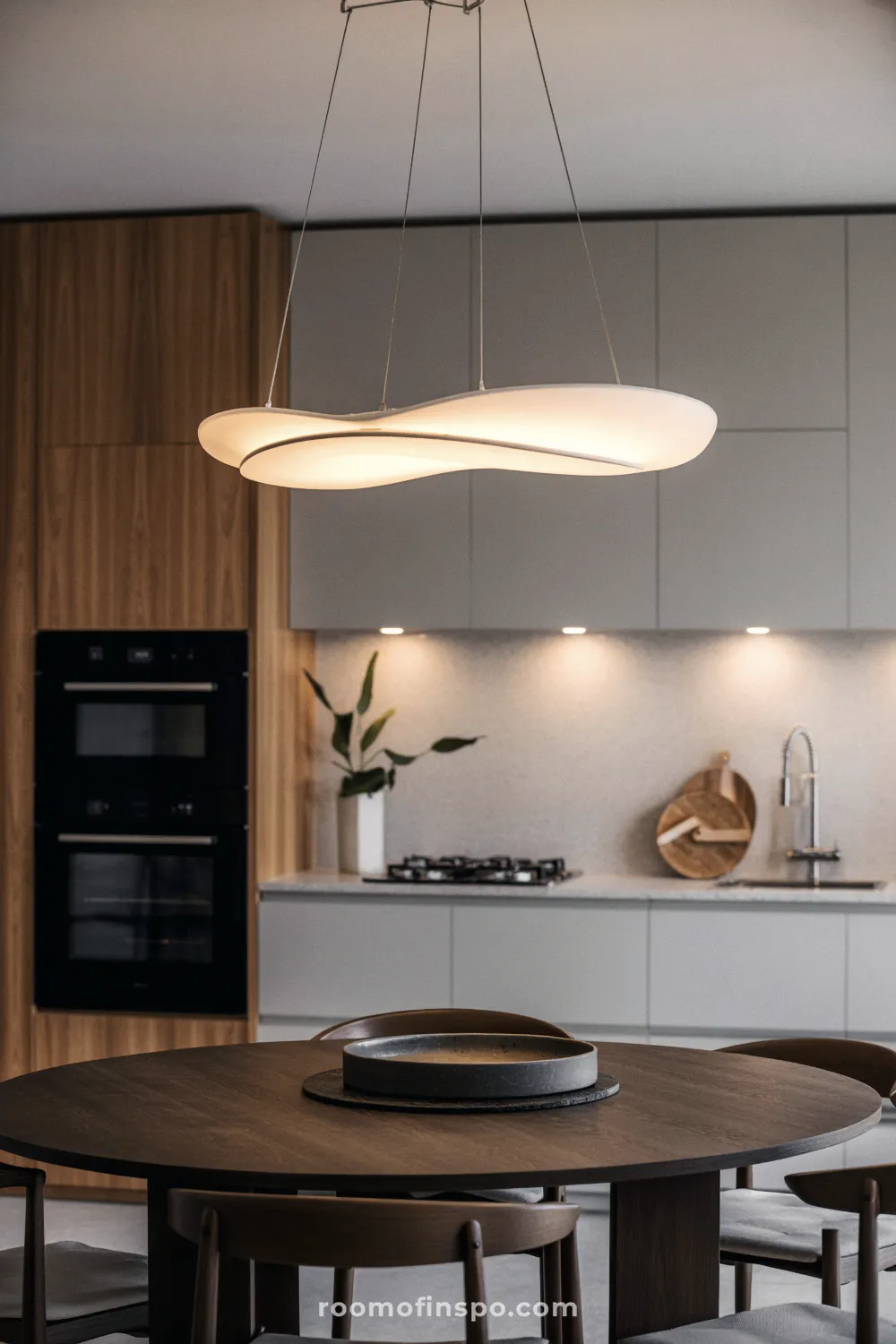 A modern kitchen featuring an expansive light-wood island and bold, sculptural pendant lighting as a central design statement.