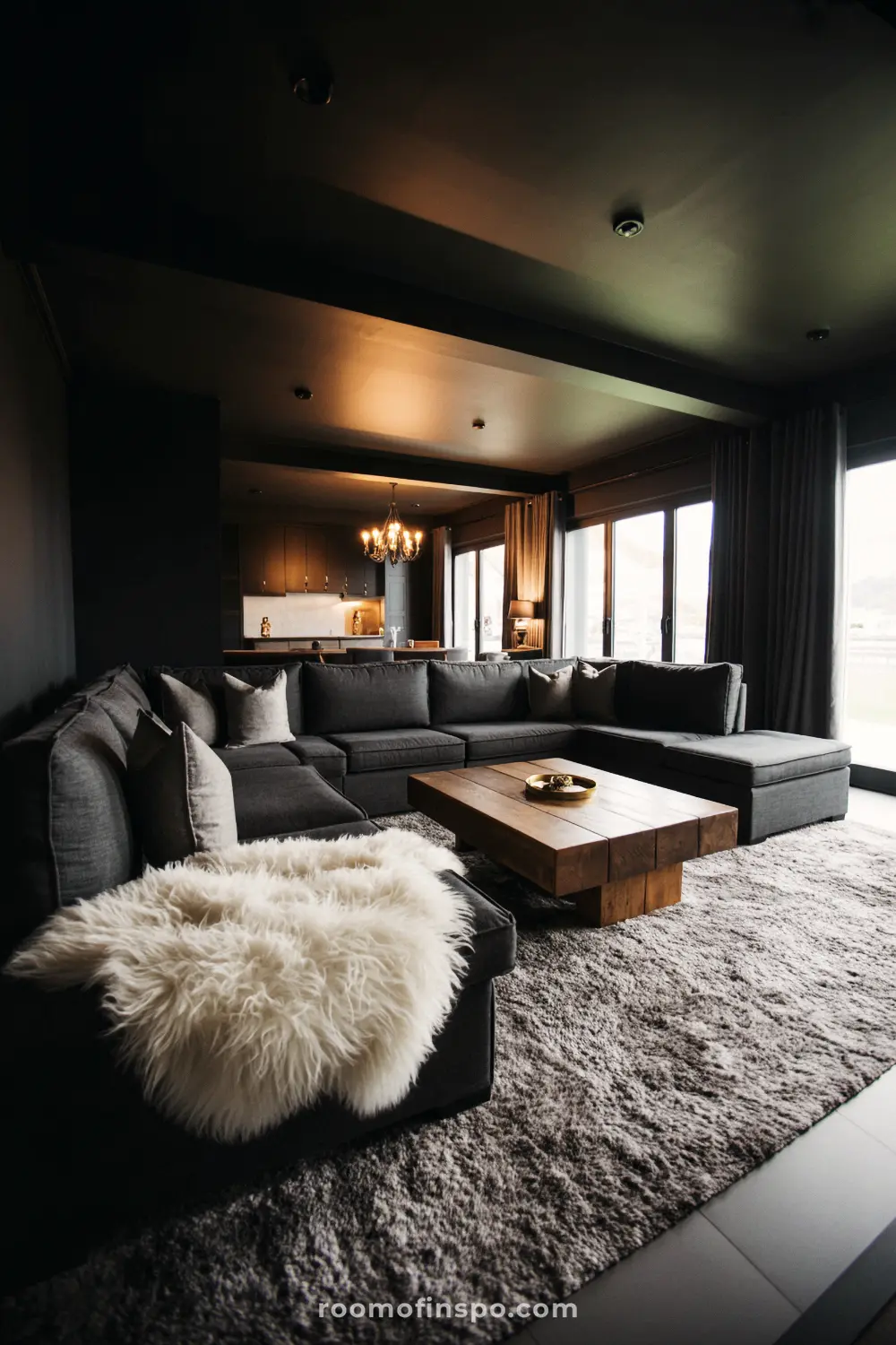 A moody, masculine living room with a large gray sectional sofa, a wooden coffee table, and a plush rug.