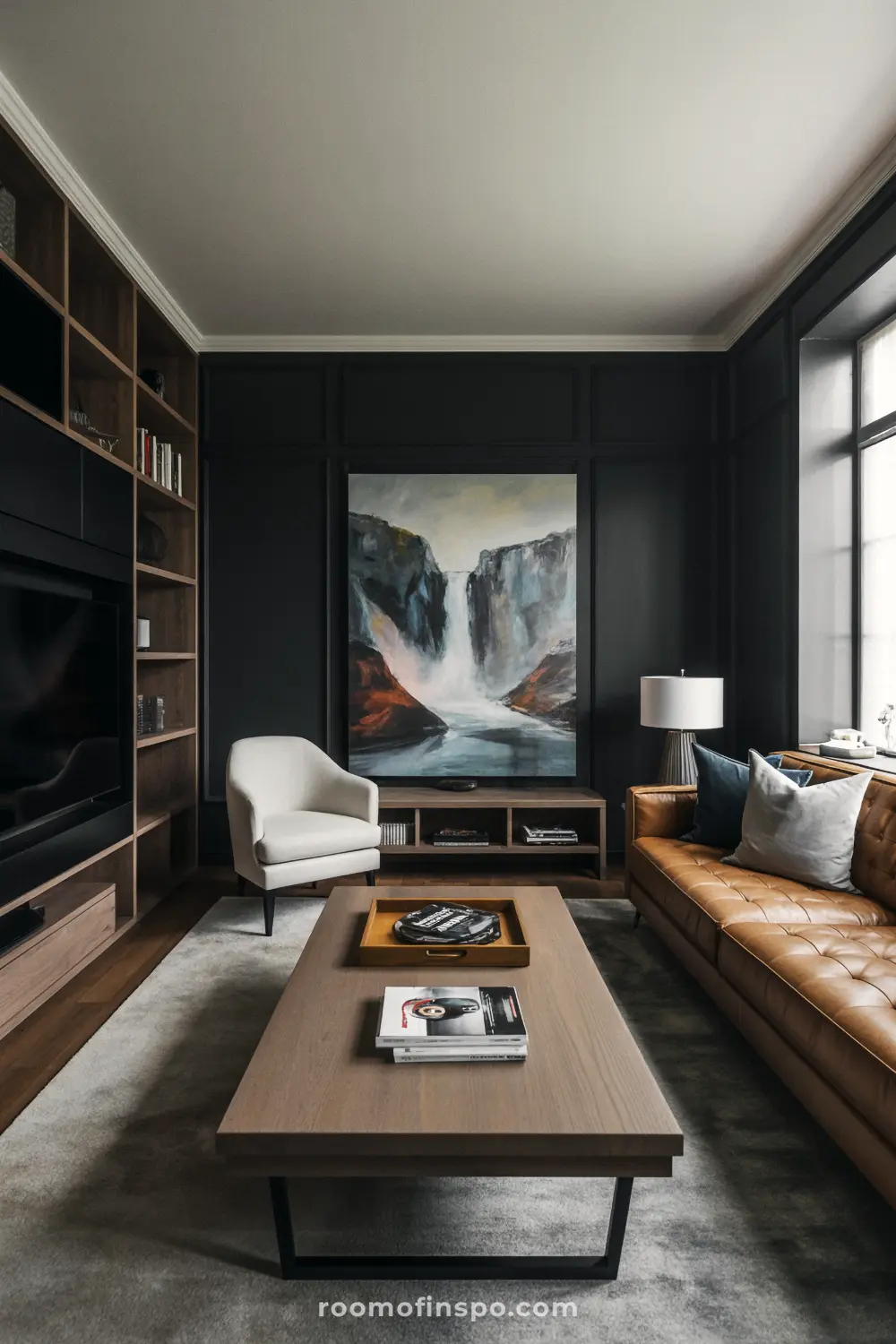 A sophisticated masculine living room with a brown leather sofa, a waterfall painting, and a floor-to-ceiling bookshelf on the left.