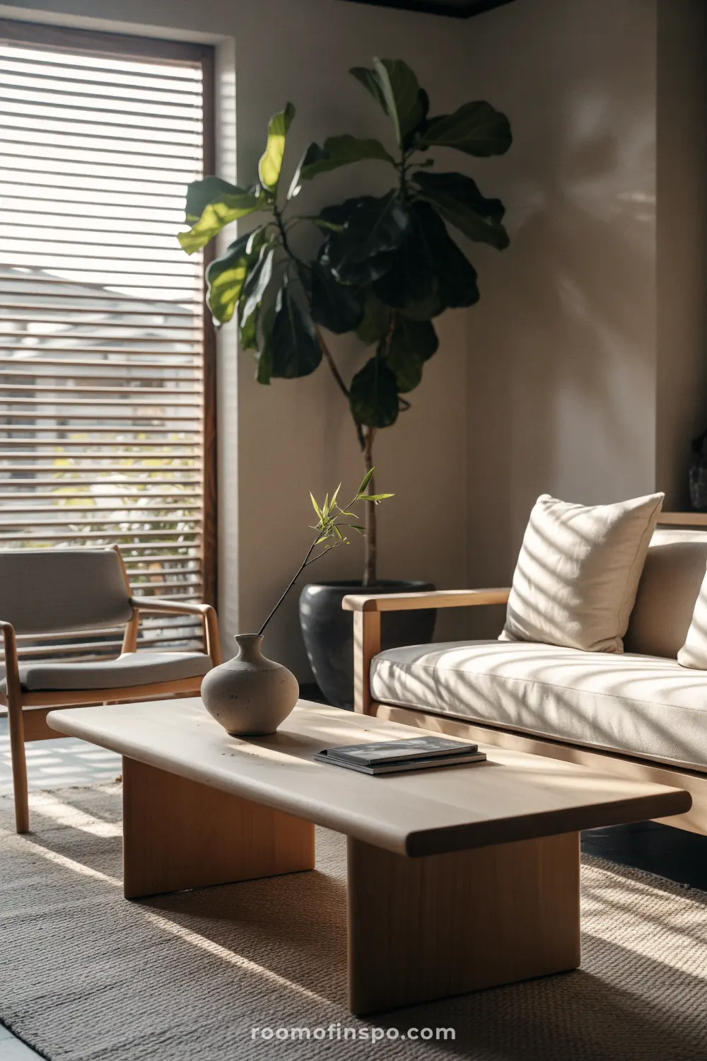 A bright Japandi-style living room for a man with a light-colored sofa, a wooden coffee table, and a tall plant.