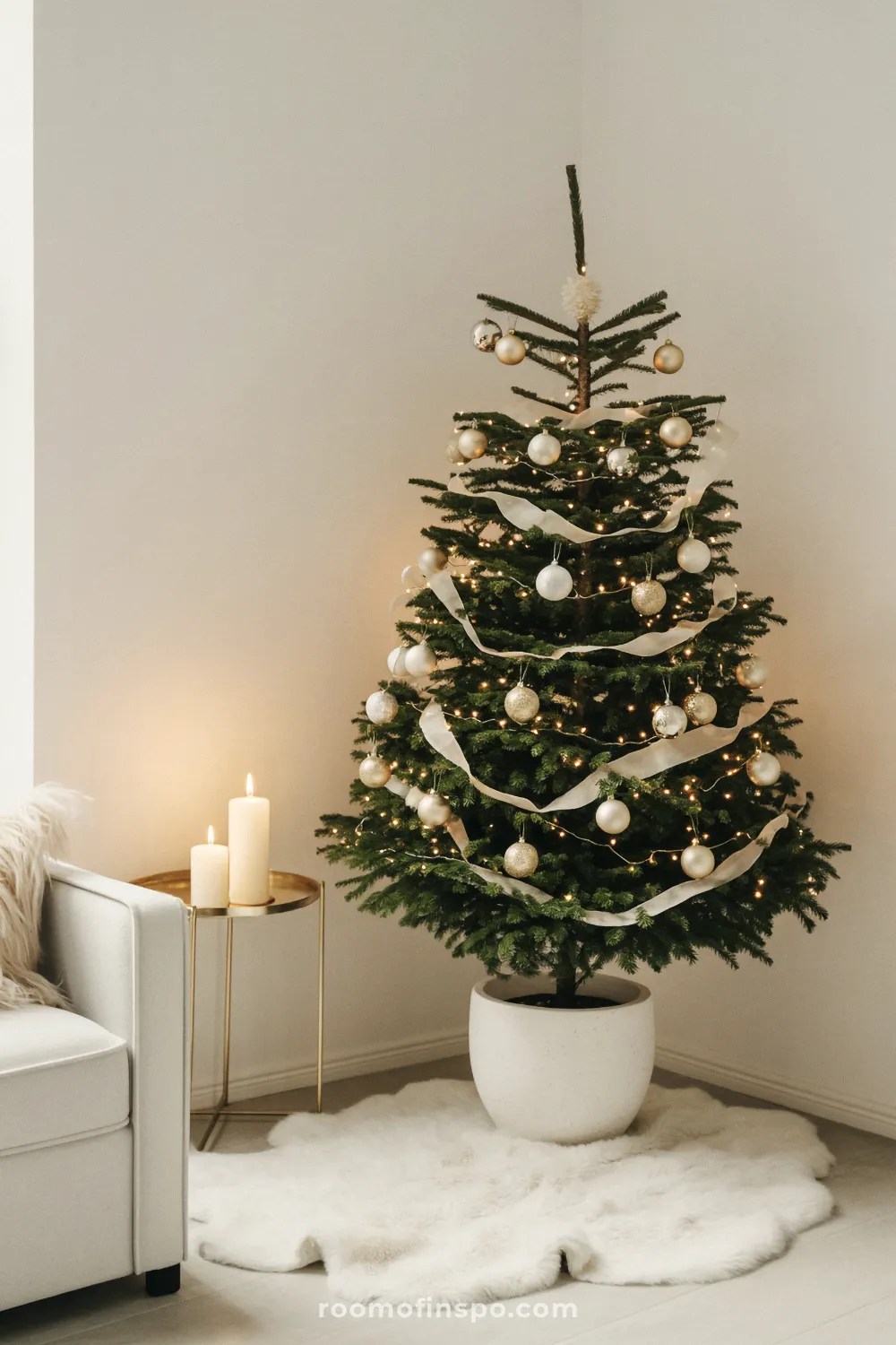 A green tree with white and gold ornaments, ribbons, and lights, defining a minimalist Christmas aesthetic.