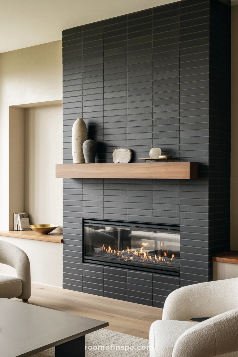 Charcoal tile fireplace with linear gas flame, white oak floating mantel, and cream boucle chairs.