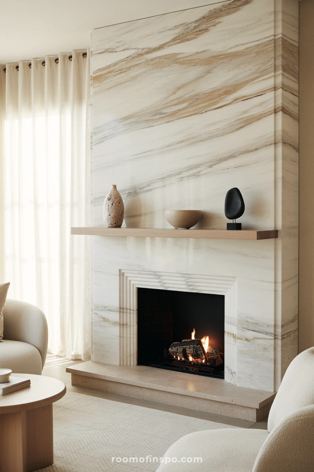 Full-height marble fireplace with ash shelf, linear firebox, cream sofa, and linen drapes in daylight.