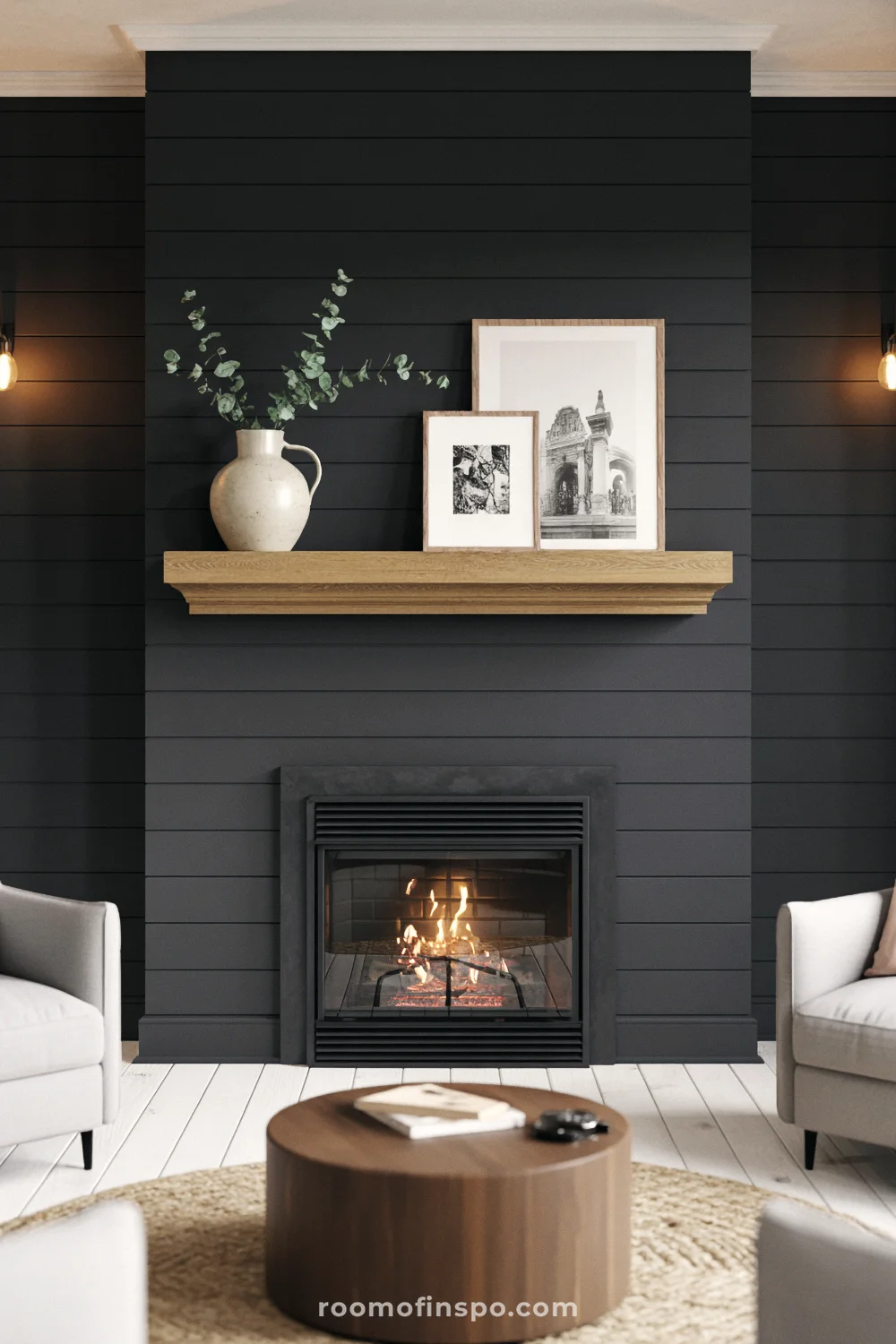 Matte black shiplap wall with floating oak mantel, black steel firebox, and light gray armchairs.