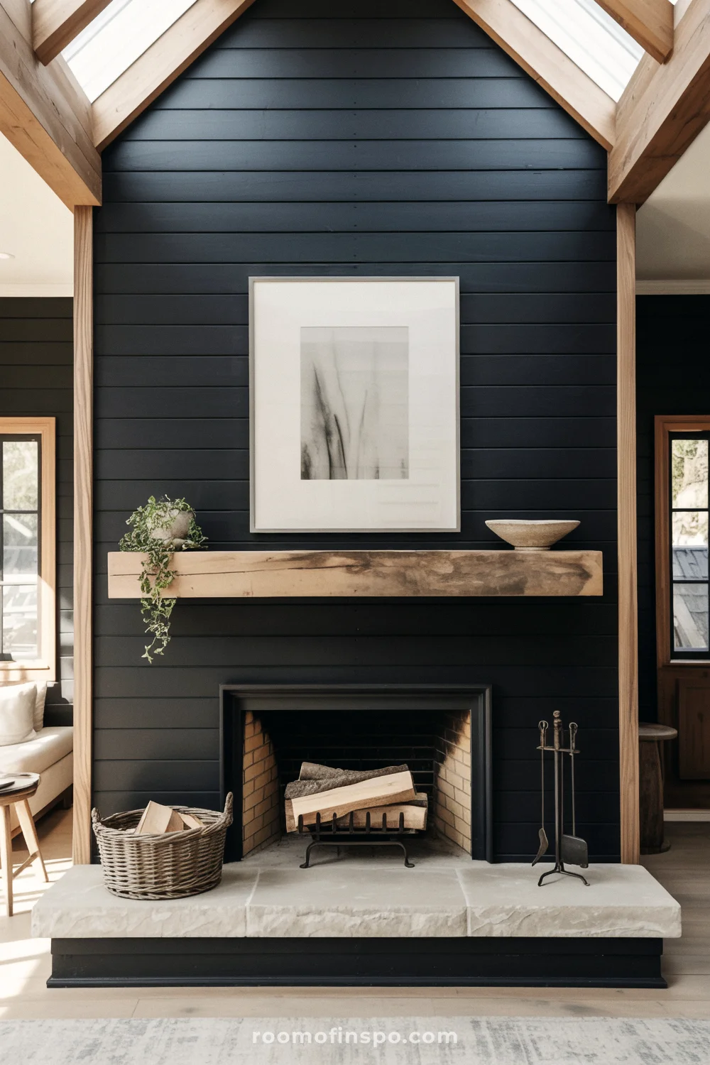 Black shiplap fireplace with reclaimed timber mantel, limestone hearth, log basket, and neutral wall art.