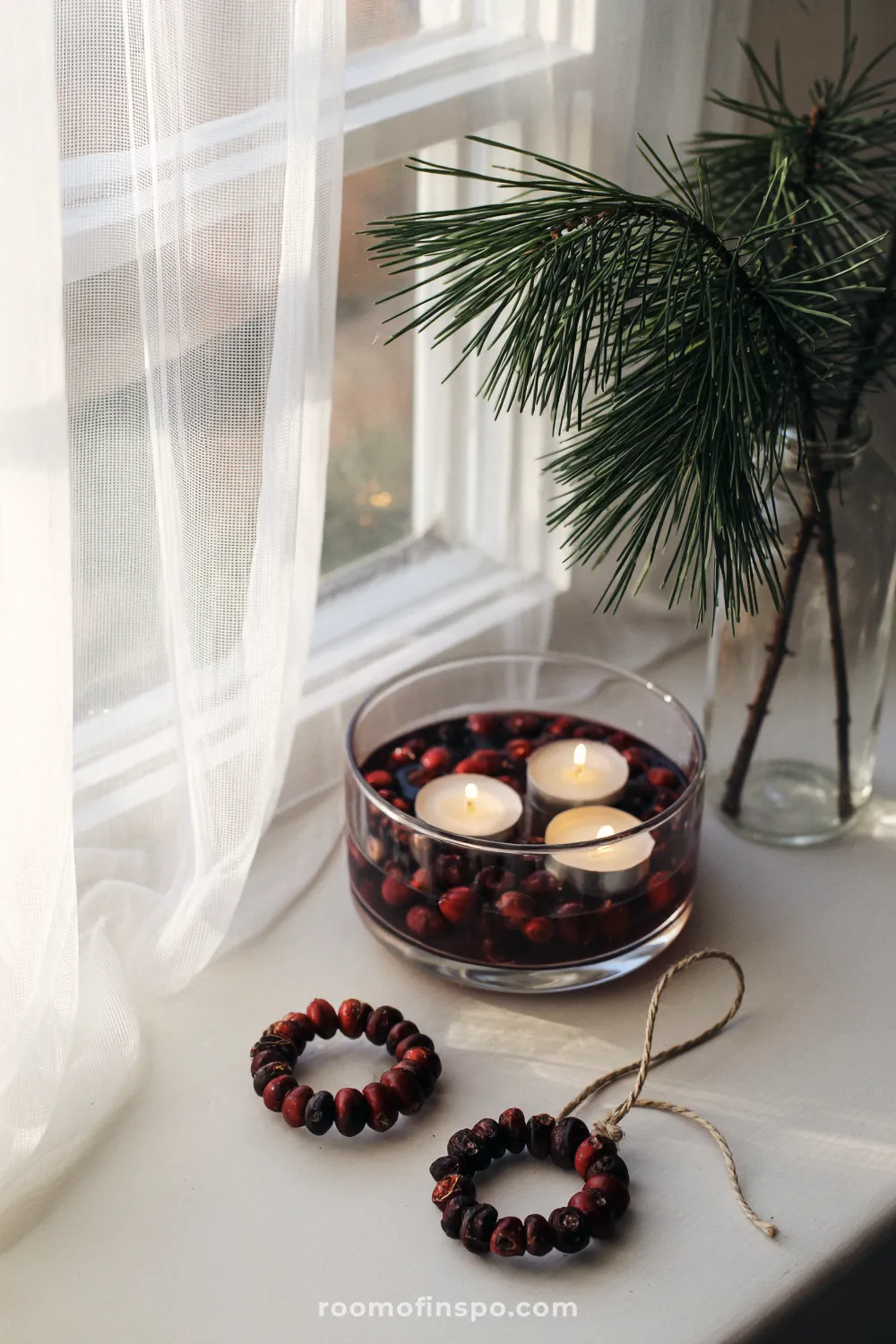 A window ledge holds floating candles in a bowl of cranberries and pine sprigs for a minimalist Christmas accent.