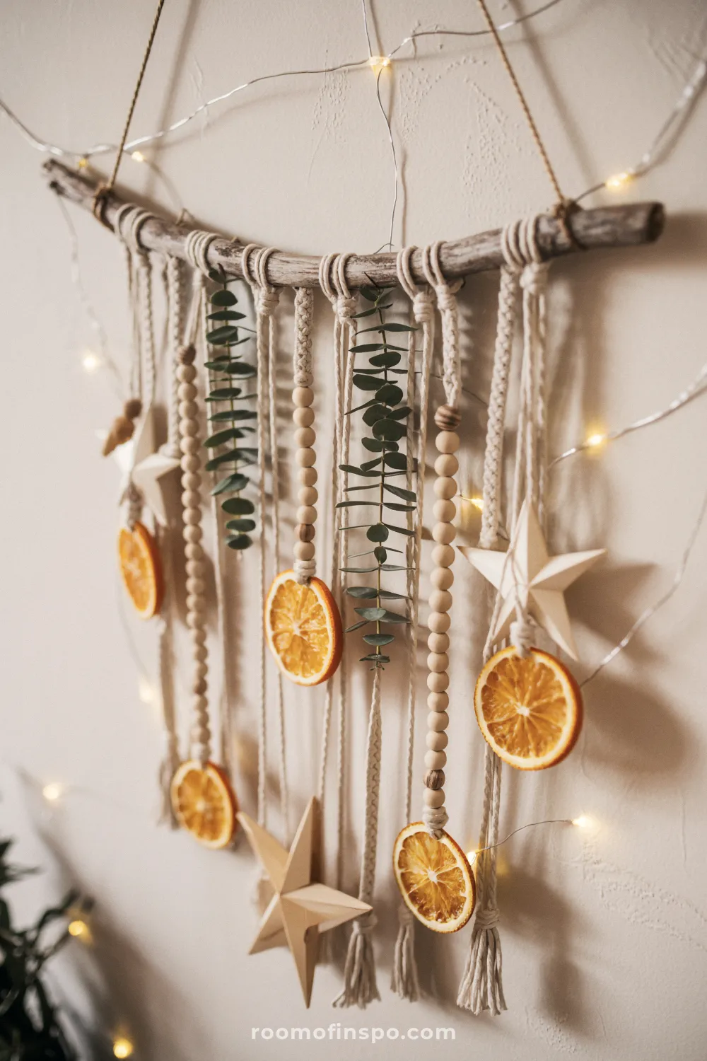 A macrame wall hanging uses a natural branch, dried orange slices, and wooden beads for festive Christmas decor.