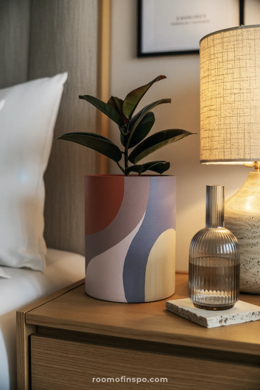 Wave-painted terracotta pot on a walnut shelf with neutral decor and soft accent lighting.