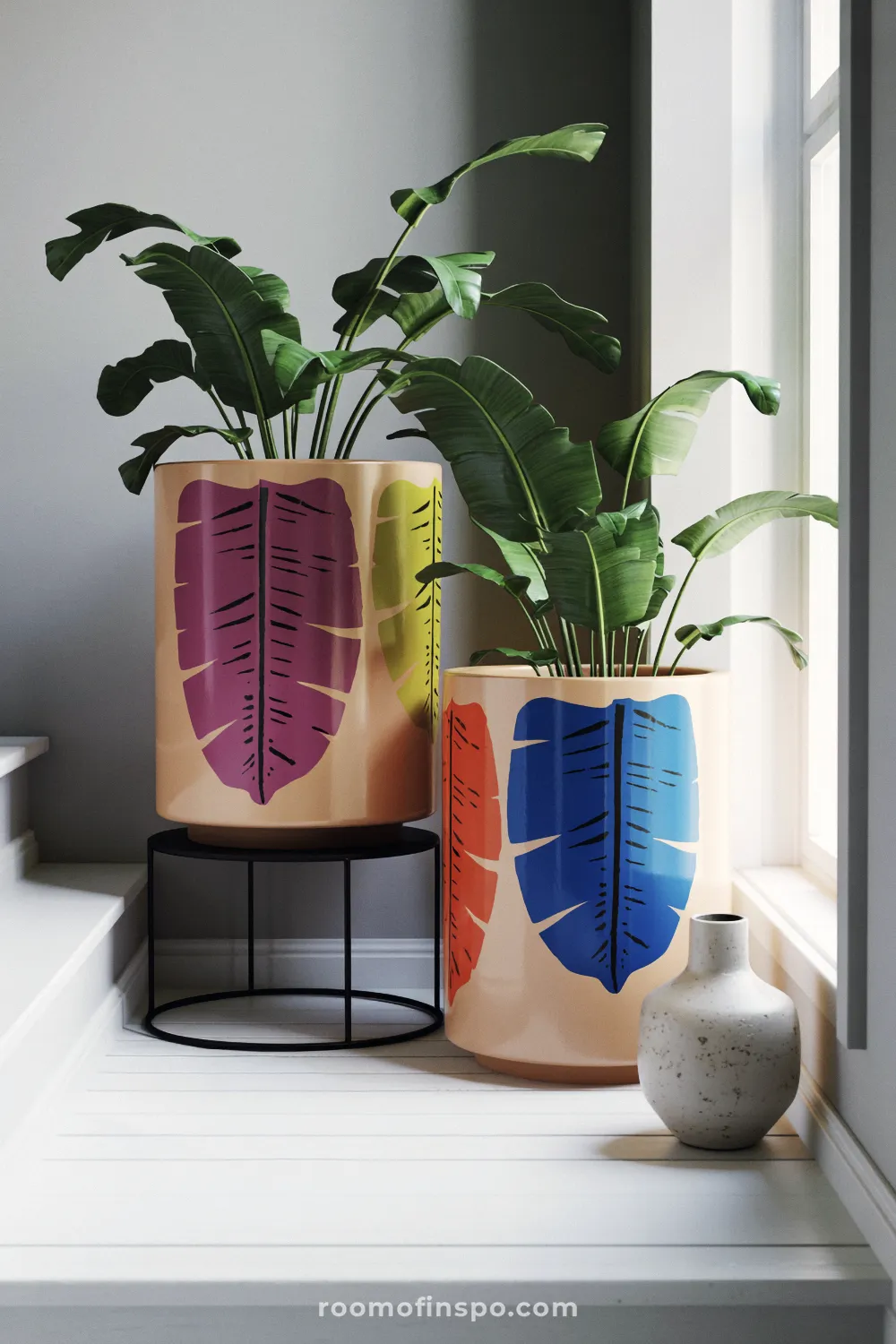Two bold leaf-painted planters on a stair landing near a window with oak flooring and a wool runner.