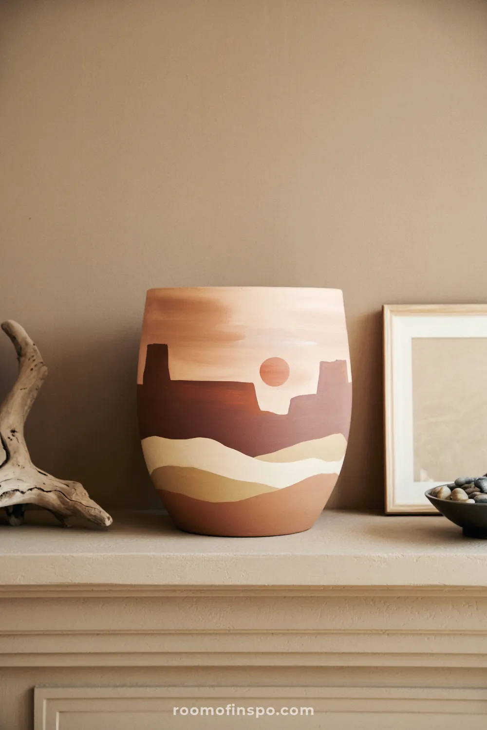 Three desert landscape-painted pots on an oak shelf under a round mirror with woven tray and neutral ceramics.