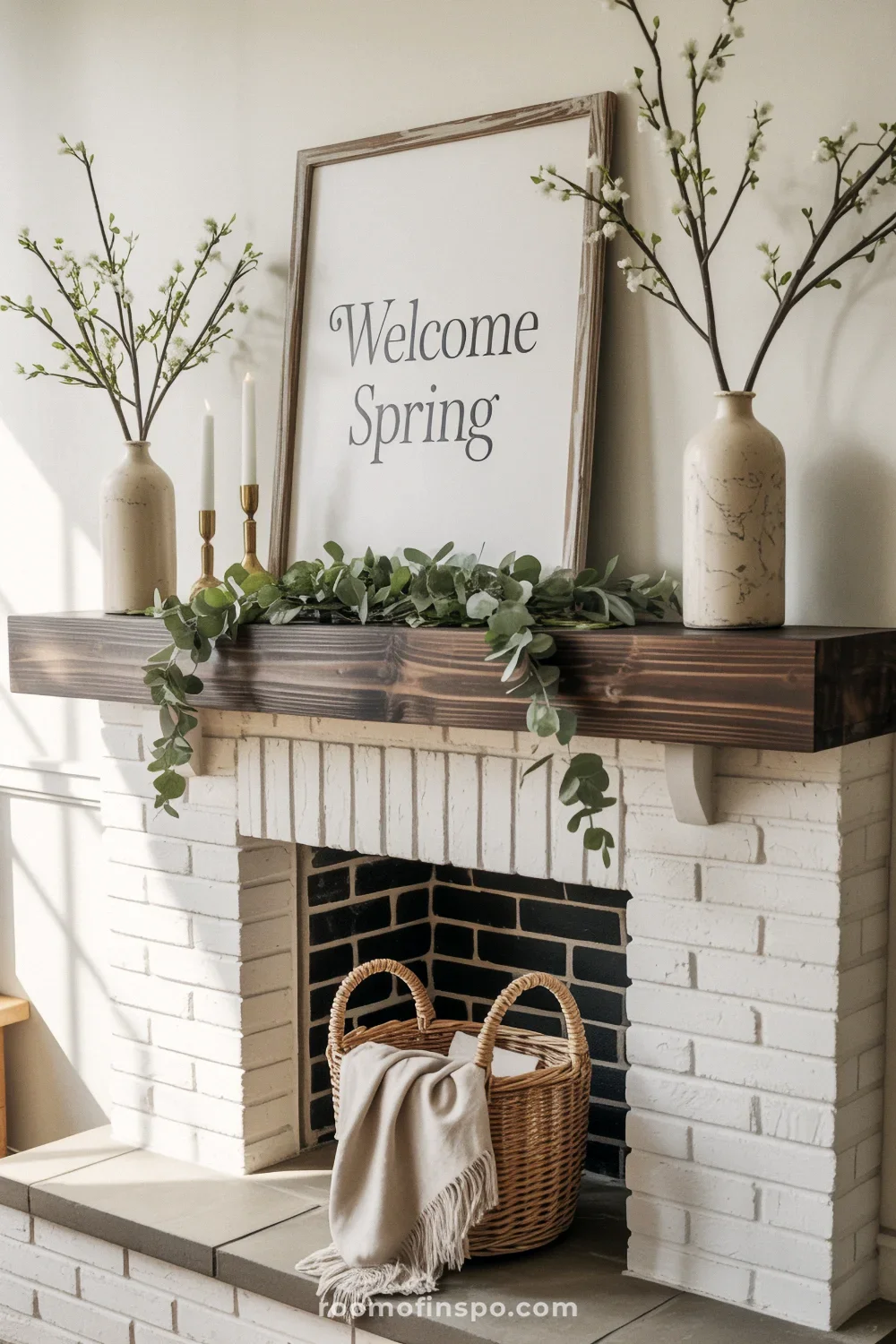 Reclaimed wood blank plaque on a mantel with eucalyptus garland, ironstone vases of branches, and brass candle holders.