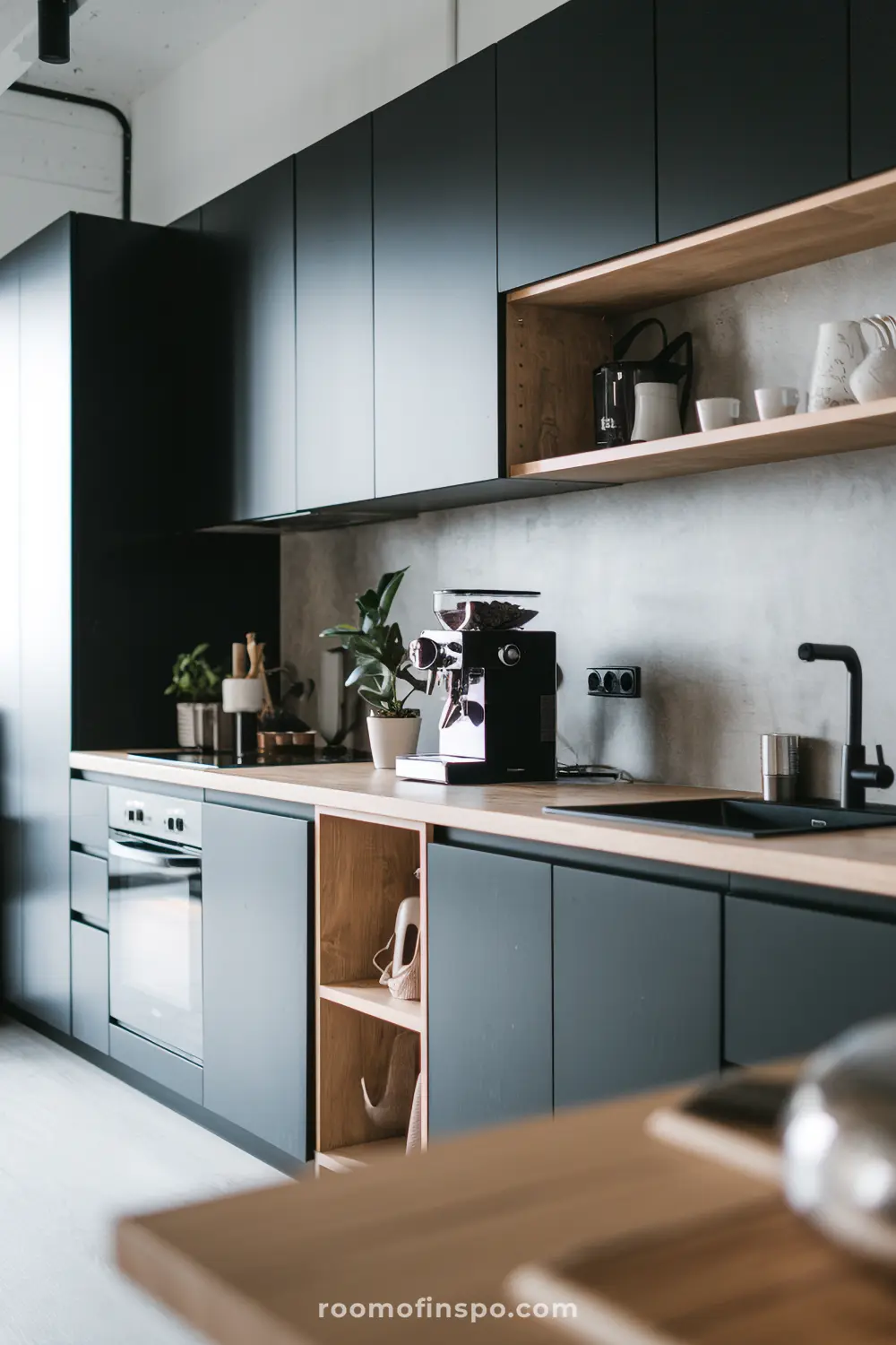 A modern Scandinavian kitchen with matte black cabinets, wooden countertops, and warm lighting.