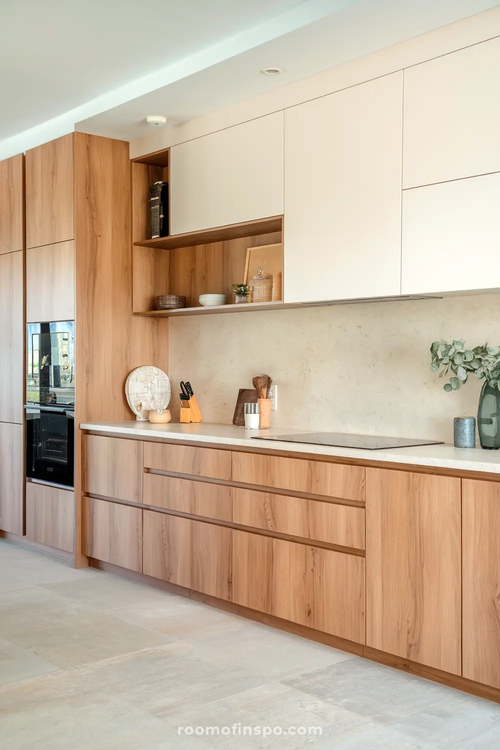 A modern Scandinavian kitchen with open shelving filled with ceramic bowls and plates, a minimalist countertop adorned with decorative items including a vase with green leaves, and a built-in oven on the right side, showcasing a clean and natural design.