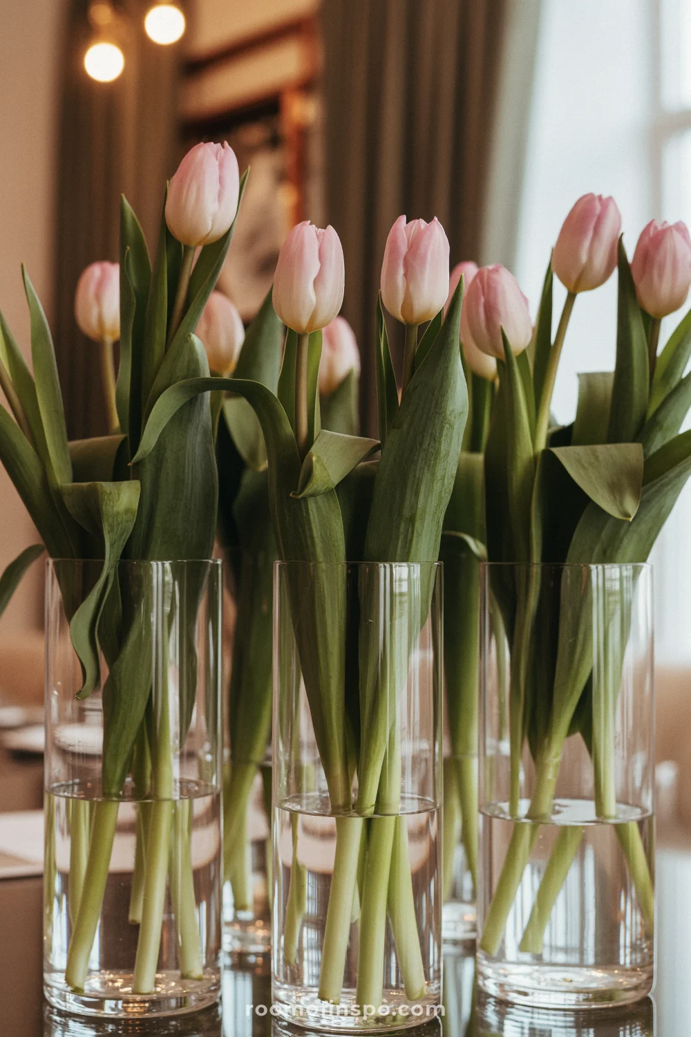 Clear glass vases with pink tulips form a modern centerpiece, emphasizing vertical rhythm and minimal elegance.