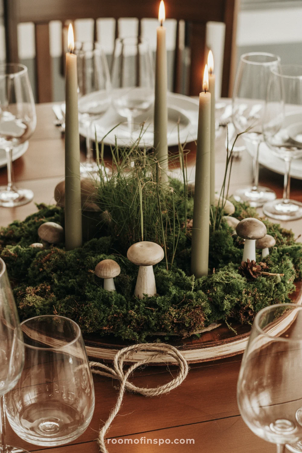 Moss, candles, and decorative mushrooms on wood create a whimsical, storybook-inspired woodland table setting.