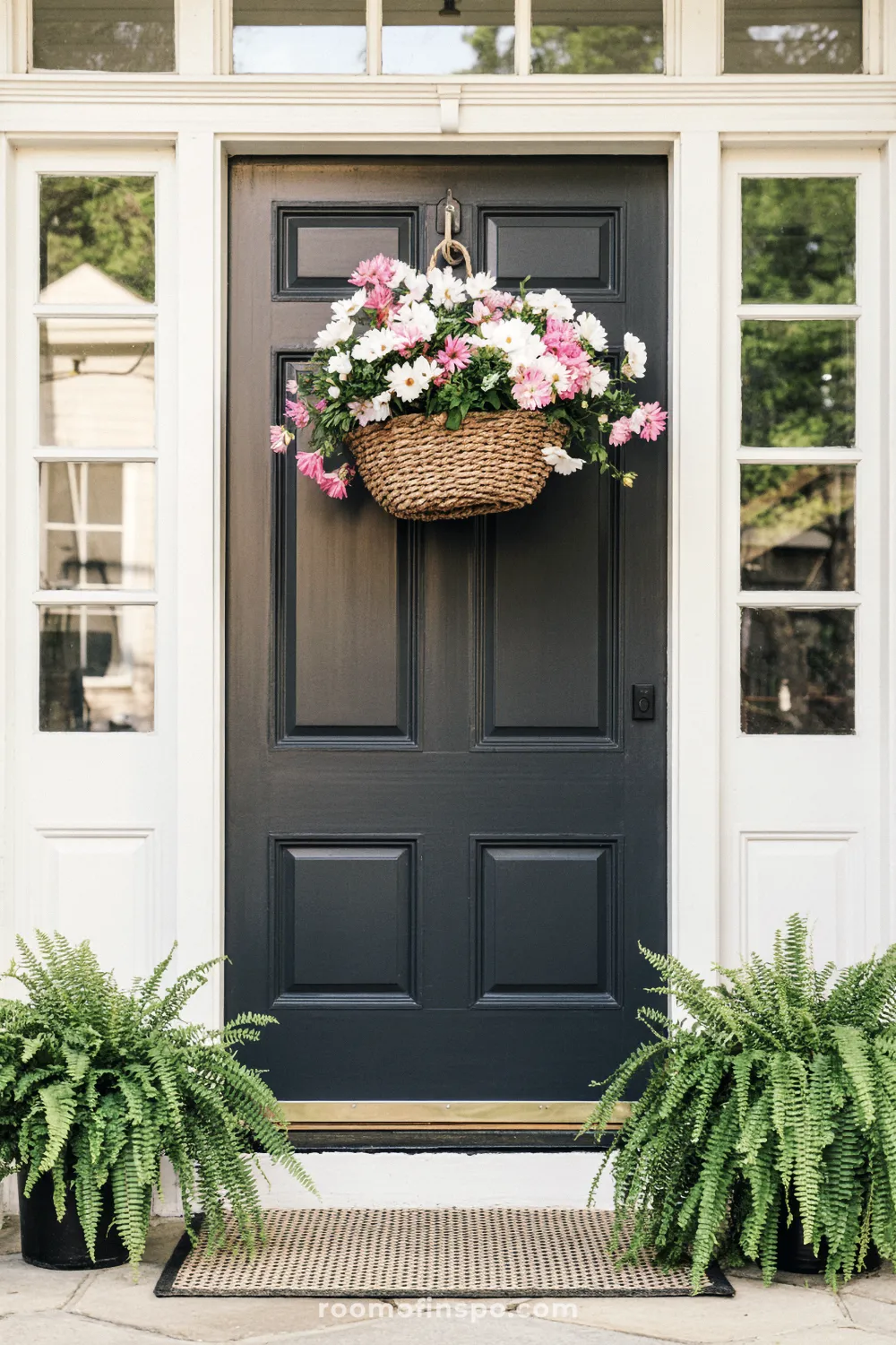 Black front door with woven basket of pink and white flowers and cozy spring accents