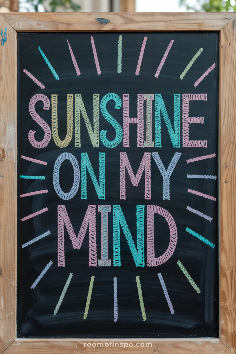 Chalkboard with "Sunshine on my mind" and sunray doodles in an indoor setting.