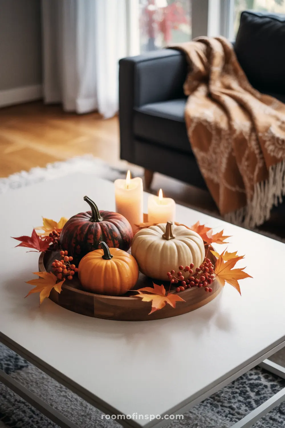 A warm Fall centerpiece featuring a wooden tray with a variety of pumpkins, berries, and autumn leaves.